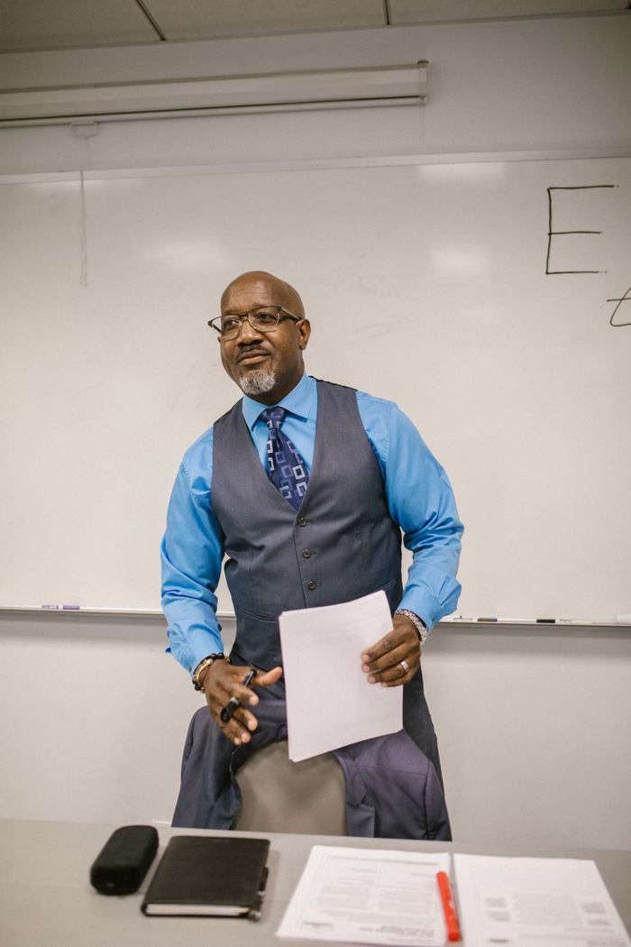 Professor standing in front of a whiteboard, teaching in a university classroom.
